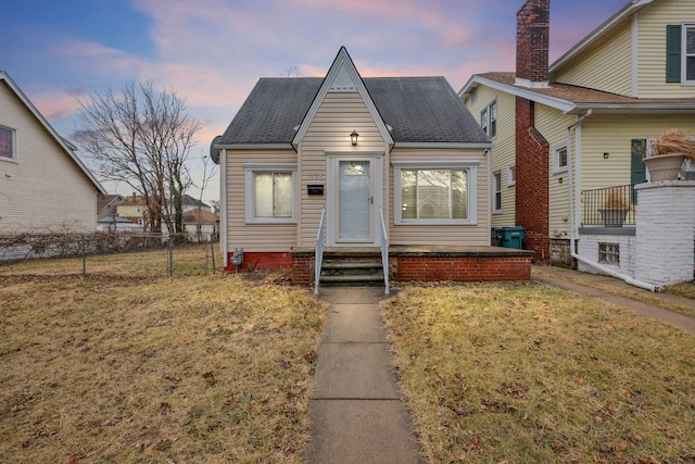 bungalow-style house featuring a shingled roof, fence, and a yard