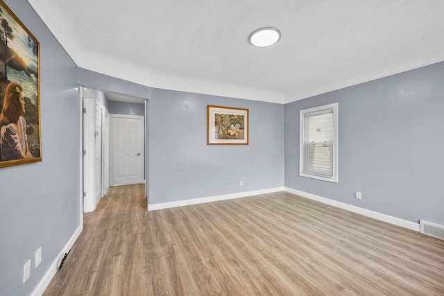 empty room with visible vents, baseboards, and wood finished floors