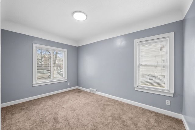 carpeted empty room featuring visible vents and baseboards