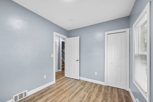 unfurnished bedroom with baseboards, visible vents, and wood finished floors