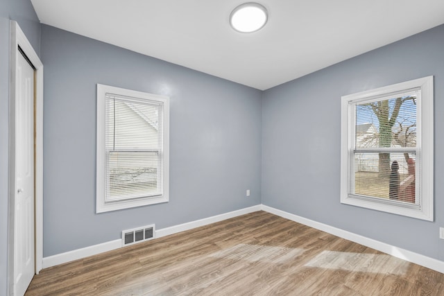 spare room with visible vents, baseboards, and wood finished floors