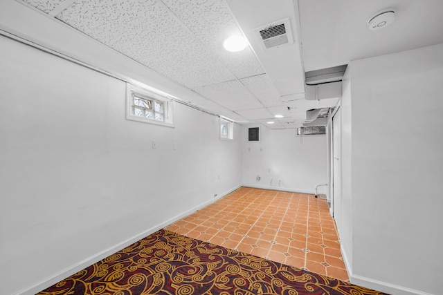 basement with a paneled ceiling, baseboards, and visible vents