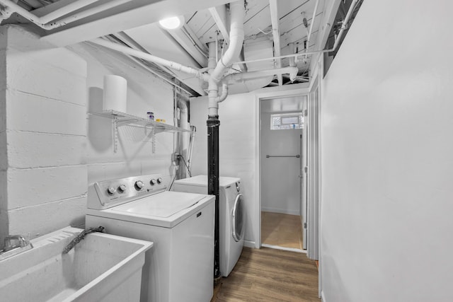 laundry room featuring laundry area, separate washer and dryer, dark wood-type flooring, a sink, and concrete block wall