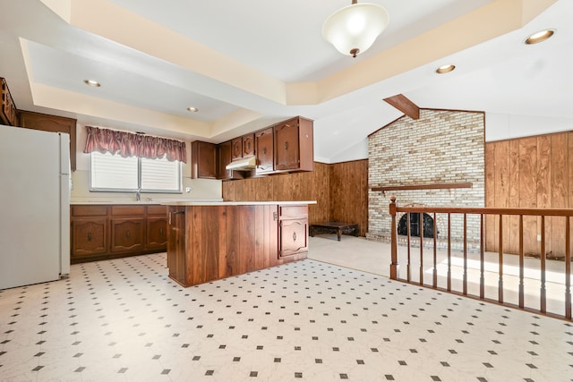 kitchen featuring vaulted ceiling with beams, wood walls, a sink, light countertops, and freestanding refrigerator