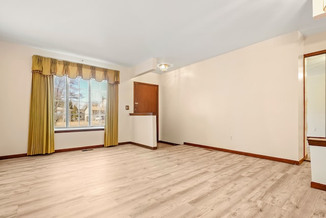 empty room featuring light wood-style floors, visible vents, and baseboards