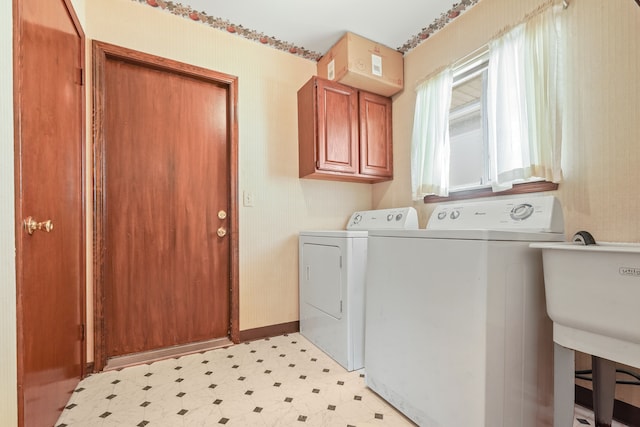 washroom with separate washer and dryer, a sink, baseboards, cabinet space, and light floors