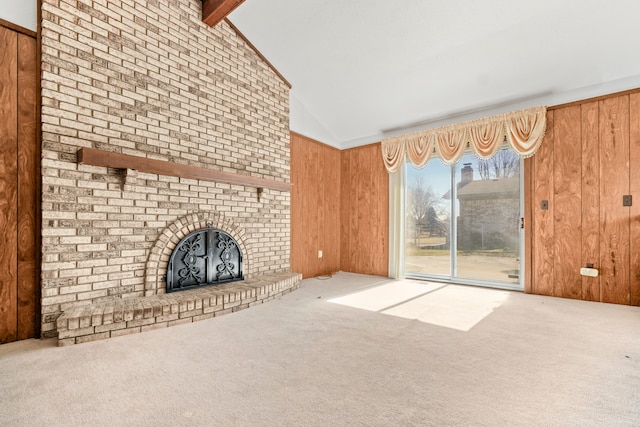 unfurnished living room with high vaulted ceiling, wooden walls, carpet floors, a fireplace, and beamed ceiling