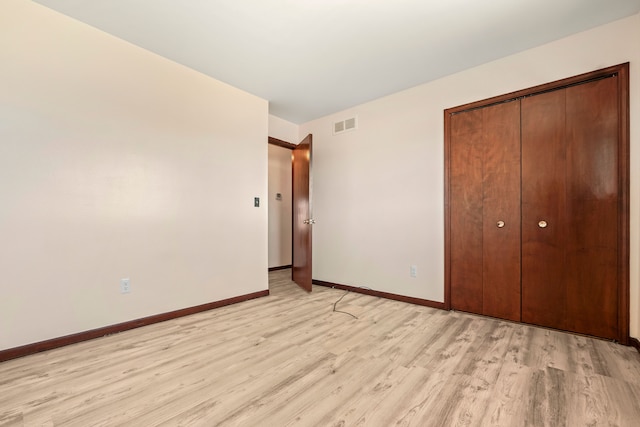 unfurnished bedroom with light wood finished floors, a closet, visible vents, and baseboards