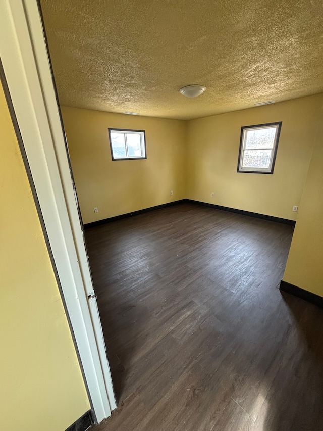 spare room with dark wood-style flooring and baseboards