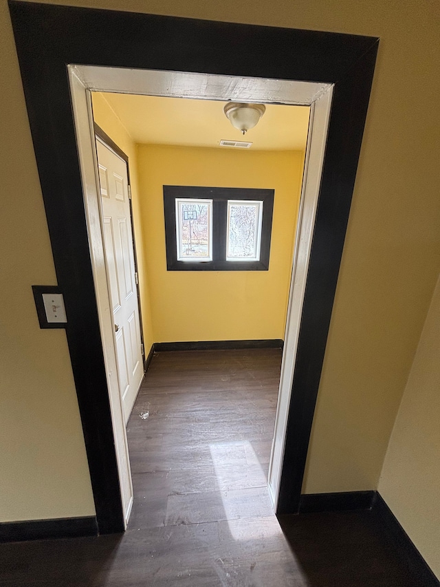 hall featuring baseboards, visible vents, and wood finished floors