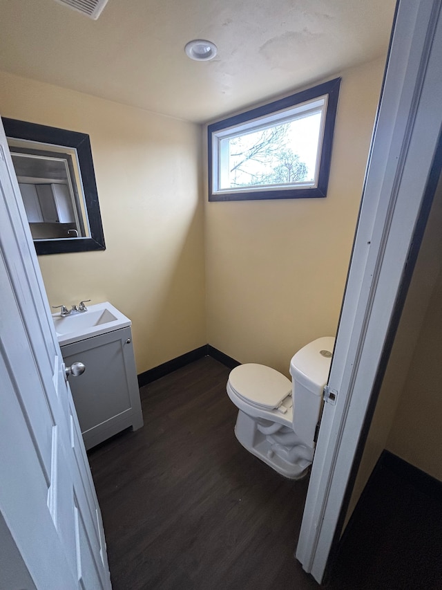 half bath featuring baseboards, vanity, toilet, and wood finished floors