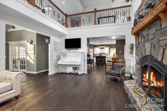 living room with dark wood-style flooring, a fireplace, a high ceiling, and french doors