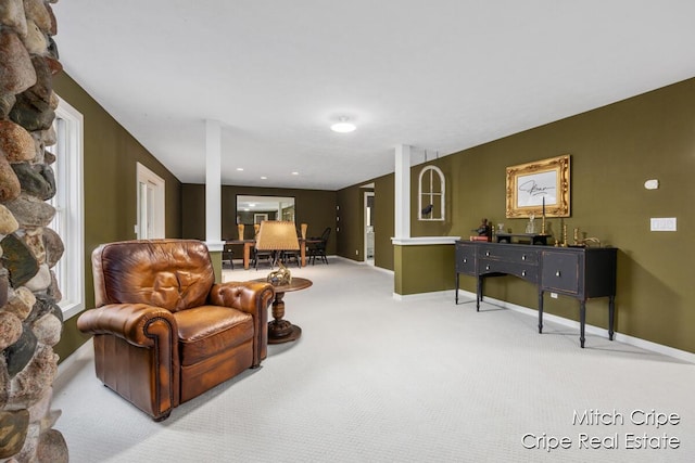 living area featuring light carpet and baseboards