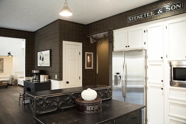 kitchen with stainless steel appliances, dark wood-style flooring, white cabinets, and wallpapered walls