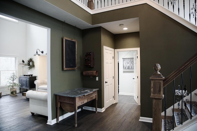 hall with stairs, dark wood-style flooring, a towering ceiling, and baseboards