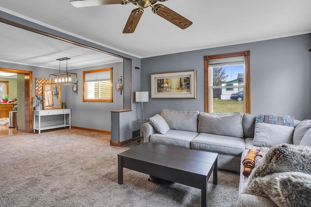 living room featuring carpet floors, ceiling fan, baseboards, and crown molding