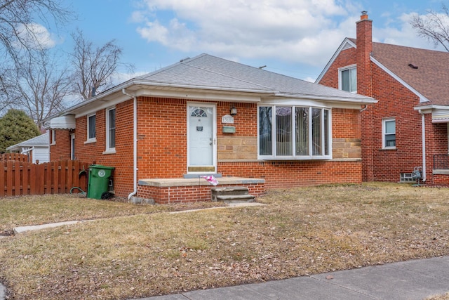 bungalow-style house with brick siding, a shingled roof, fence, stone siding, and a front lawn