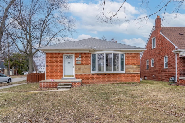 bungalow with brick siding, a front lawn, a shingled roof, and fence