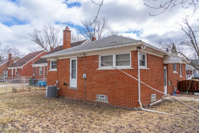 back of house with brick siding, a chimney, fence, and central air condition unit