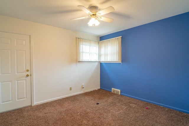 carpeted empty room with baseboards, visible vents, and a ceiling fan