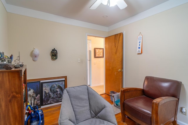 sitting room featuring baseboards, a ceiling fan, and wood finished floors