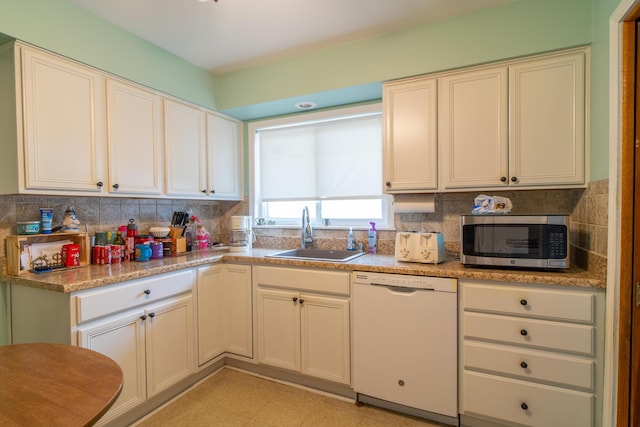 kitchen with tasteful backsplash, stainless steel microwave, white dishwasher, and a sink