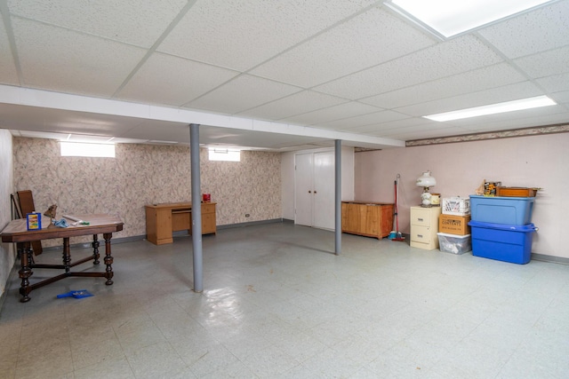 basement featuring baseboards, a drop ceiling, and tile patterned floors