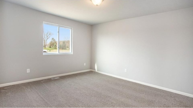 carpeted spare room featuring visible vents and baseboards