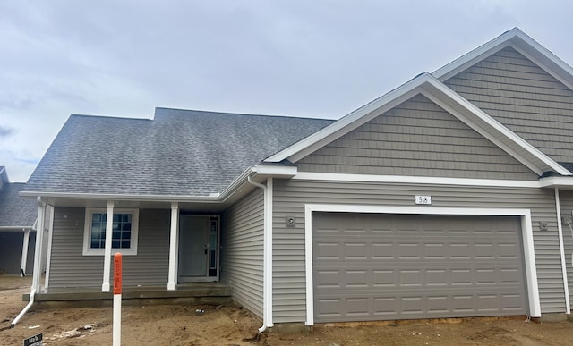 ranch-style house featuring a garage and roof with shingles