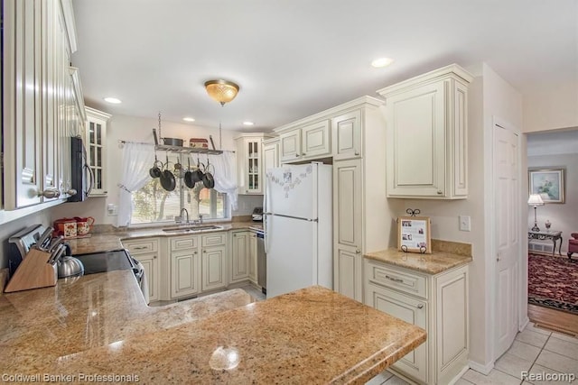 kitchen with electric stove, glass insert cabinets, freestanding refrigerator, a sink, and black microwave