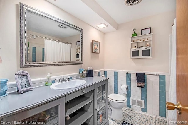 bathroom featuring tile walls, visible vents, toilet, wainscoting, and tile patterned floors