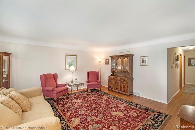 living room with wood finished floors, visible vents, and baseboards