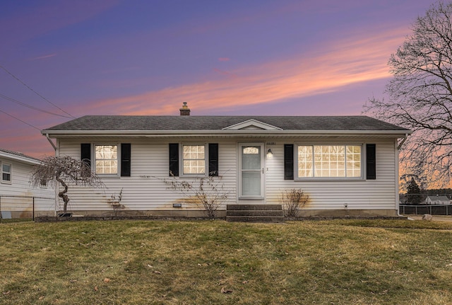 view of front of house with entry steps, a lawn, a chimney, and fence