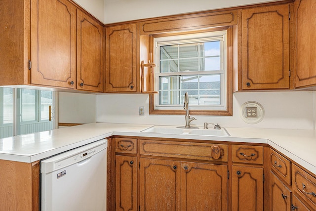 kitchen featuring dishwasher, light countertops, brown cabinetry, and a sink