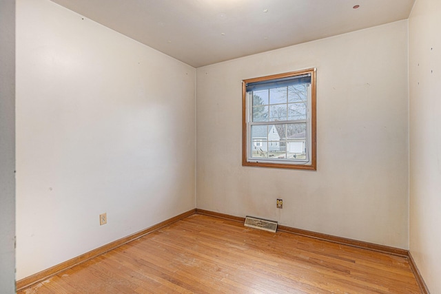 spare room featuring visible vents, light wood-style flooring, and baseboards