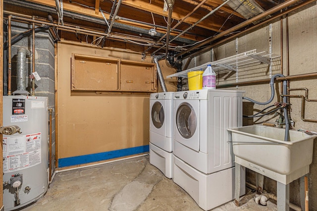 washroom with laundry area, washing machine and dryer, water heater, and a sink