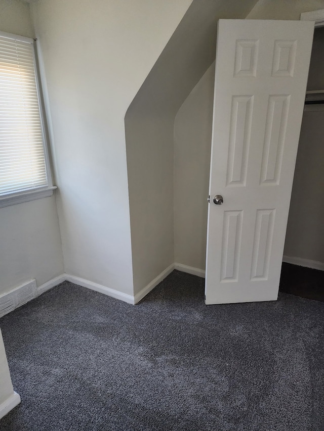 bonus room with dark colored carpet, visible vents, and baseboards