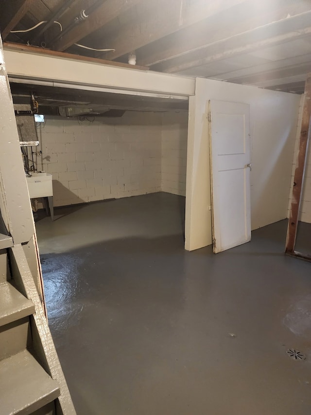 unfinished basement with a sink and concrete block wall