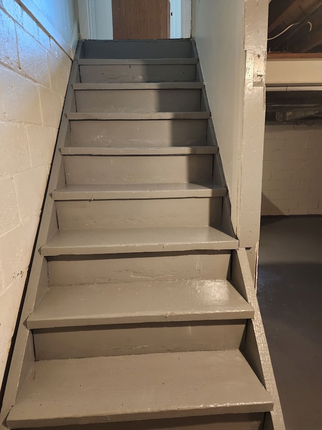 staircase featuring concrete flooring and concrete block wall