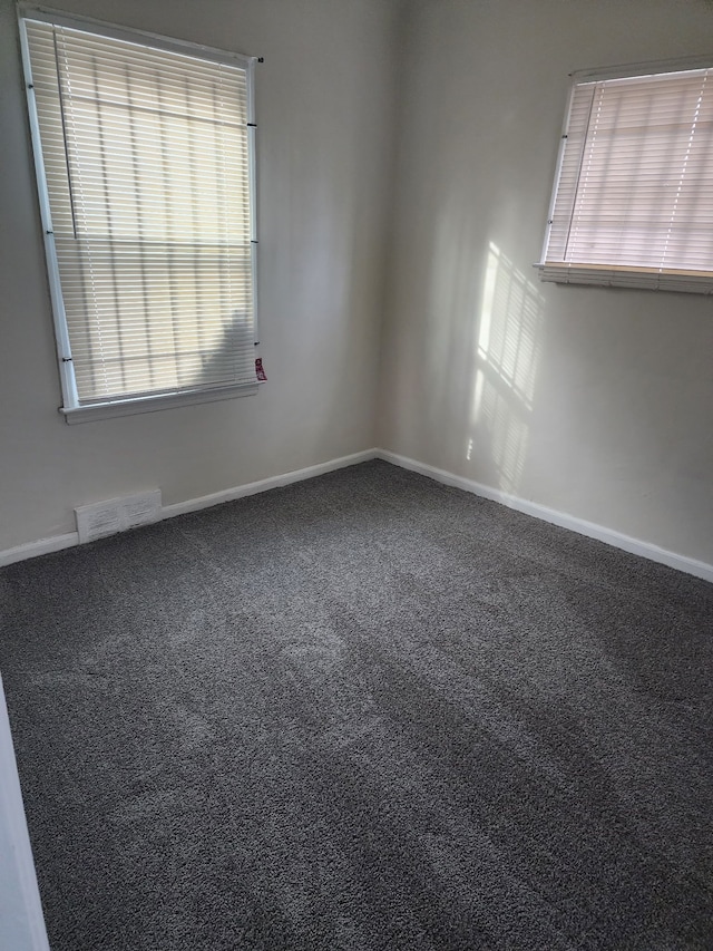 empty room with carpet, visible vents, and baseboards