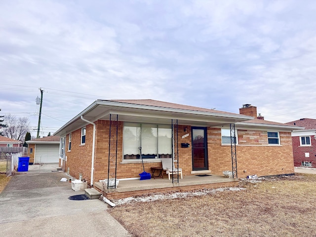 view of front facade featuring covered porch, a detached garage, and brick siding