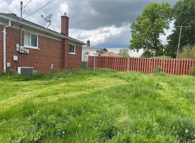 view of yard with central AC unit and fence