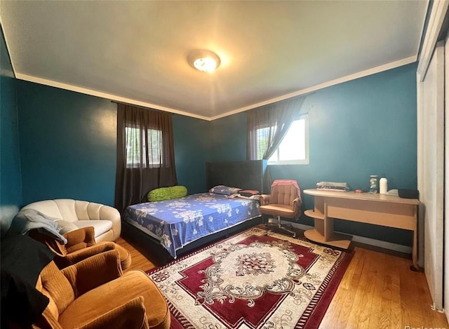 bedroom with wood finished floors and crown molding