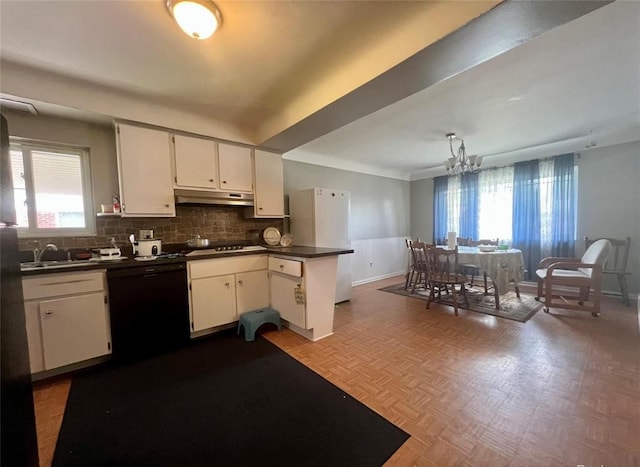 kitchen featuring under cabinet range hood, a peninsula, freestanding refrigerator, dishwasher, and dark countertops