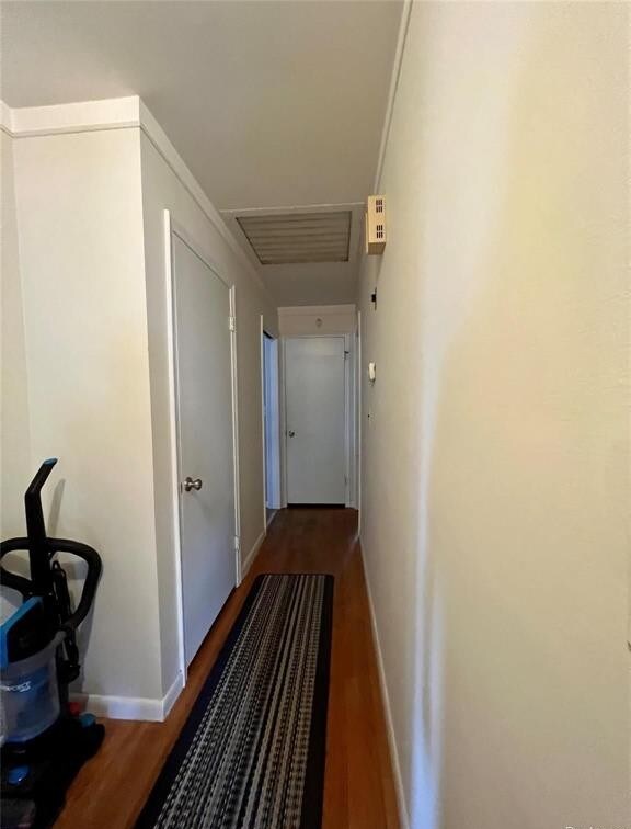 hallway with visible vents, baseboards, and wood finished floors