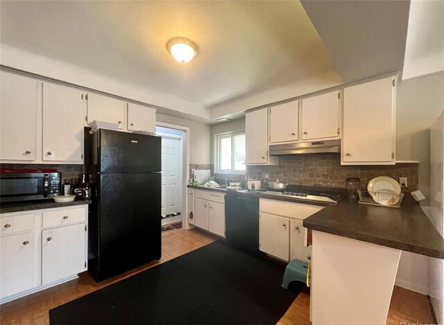 kitchen with dark countertops, black appliances, under cabinet range hood, and white cabinets