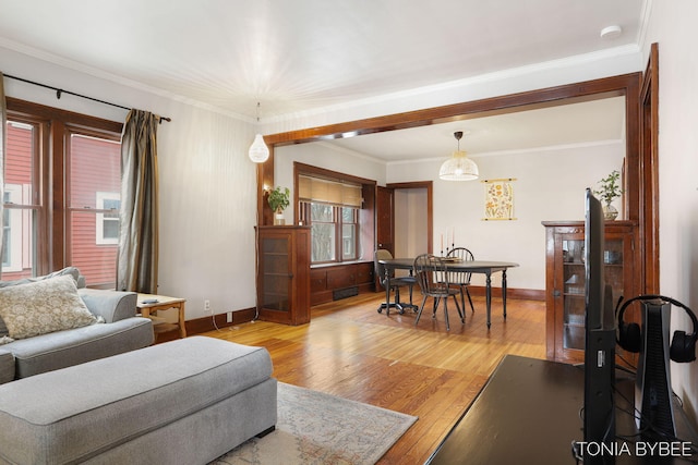 living room featuring crown molding, baseboards, visible vents, and light wood-style floors