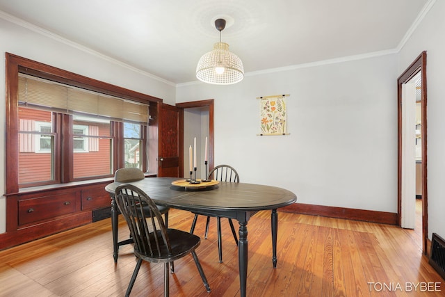 dining room with ornamental molding, light wood-style flooring, and baseboards