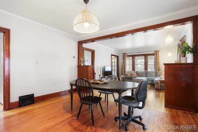 dining space with visible vents, wood finished floors, and ornamental molding