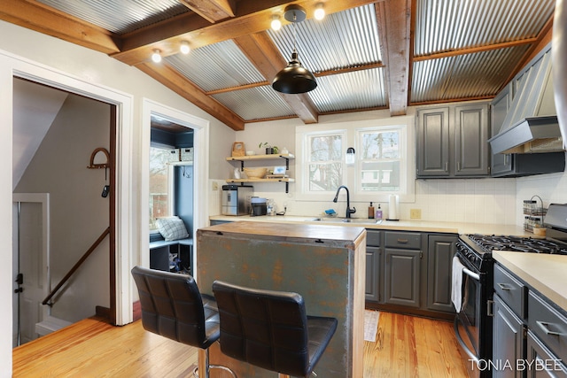 kitchen with a sink, wooden counters, light wood-type flooring, backsplash, and stainless steel range with gas cooktop